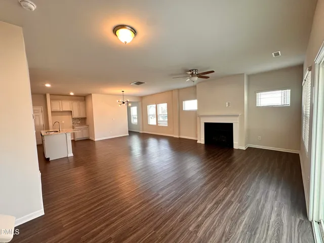 a view of empty room with wooden floor and a fireplace