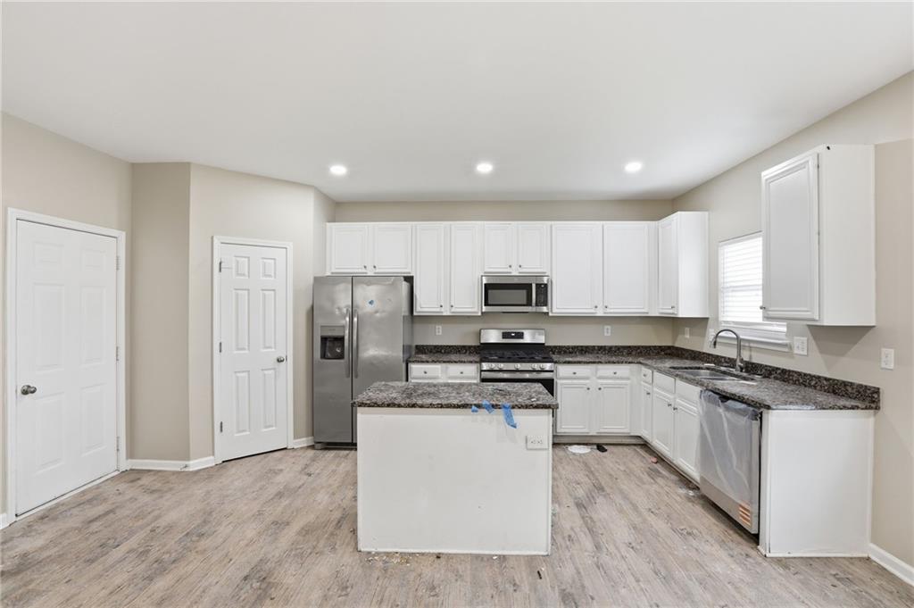 4968 Locherby Drive Fairburn, GA 30213 - Photo 14 of 39 a kitchen with stainless steel appliances granite countertop a stove top oven a refrigerator a sink and dishwasher with wooden floor
