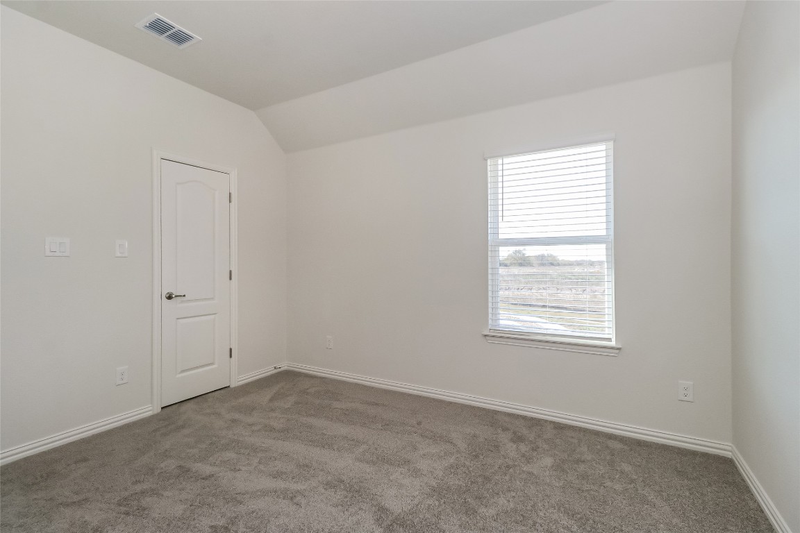 530 Ansley Court Taylor, TX 76574 - Photo 16 of 31 Carpeted empty room with vaulted ceiling and baseboards