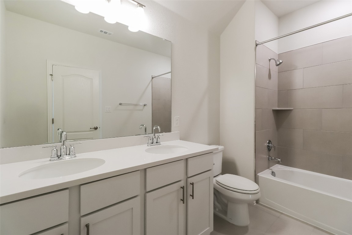 530 Ansley Court Taylor, TX 76574 - Photo 24 of 31 Full bath featuring double vanity, shower combination, and light tile patterned floors
