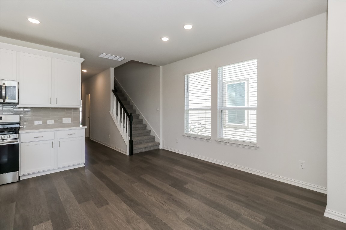 530 Ansley Court Taylor, TX 76574 - Photo 3 of 31 Kitchen featuring stainless steel appliances, decorative backsplash, white cabinetry, recessed lighting, and dark wood-style flooring