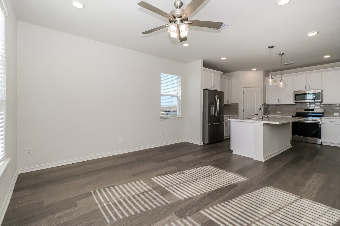 530 Ansley Court Taylor, TX 76574 - Photo 5 of 31 Kitchen with appliances with stainless steel finishes, decorative light fixtures, a kitchen island with sink, white cabinets, and dark wood-style flooring
