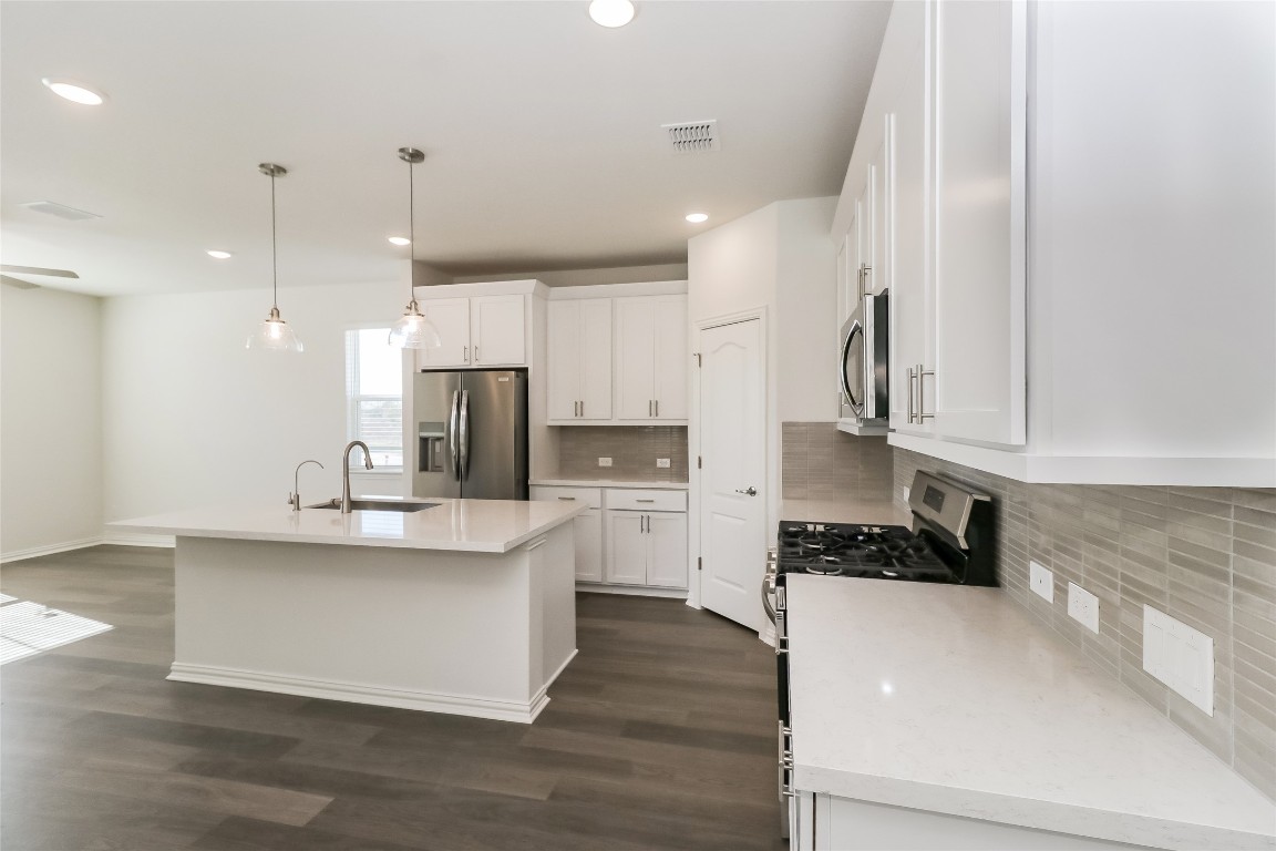 530 Ansley Court Taylor, TX 76574 - Photo 6 of 31 Kitchen with tasteful backsplash, pendant lighting, stainless steel appliances, a kitchen island with sink, and white cabinetry
