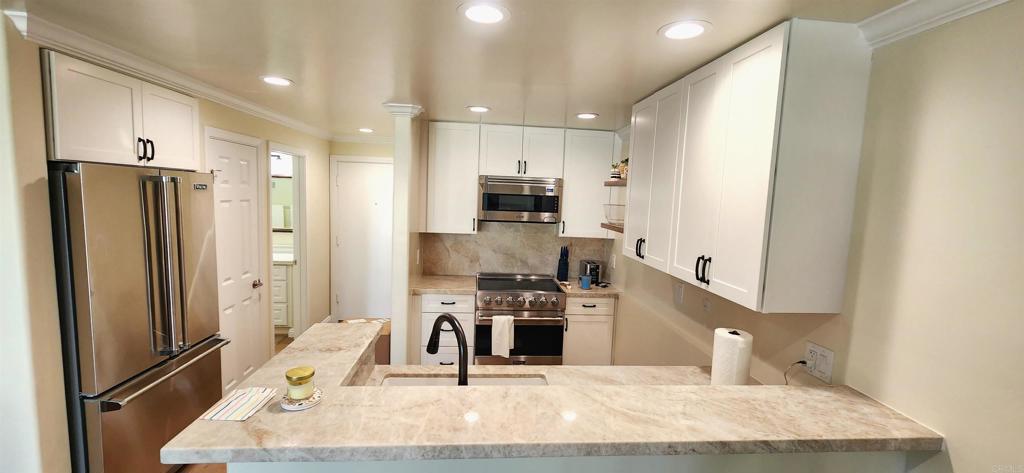 2005 Costa Del Mar Road, Unit 619 Carlsbad, CA 92009 - Photo 11 of 23 a kitchen with stainless steel appliances kitchen island granite countertop a refrigerator and a stove top oven