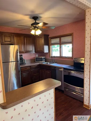 a kitchen with granite countertop a refrigerator a sink dishwasher a stove and white cabinets