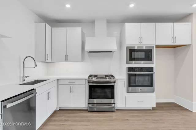 a kitchen with white cabinets stainless steel appliances and wooden floor