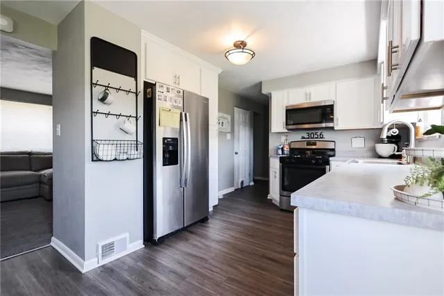 a kitchen with stainless steel appliances granite countertop a refrigerator a stove top oven a sink dishwasher and wooden floor