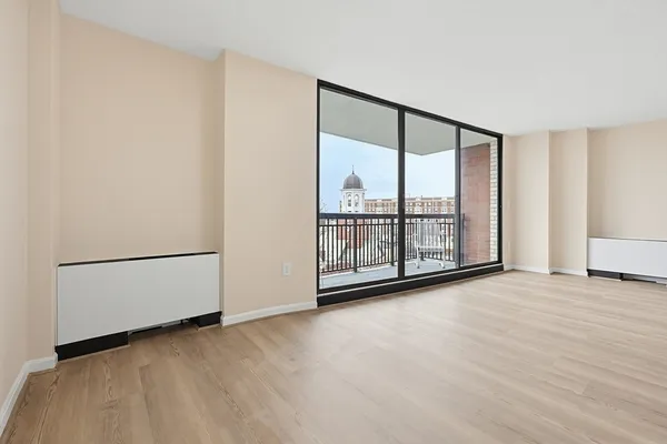 a view of an empty room with wooden floor and a window
