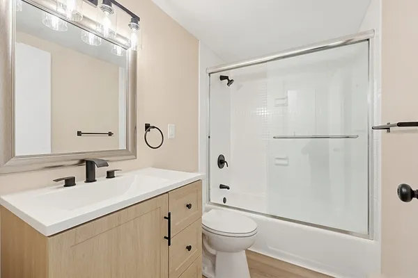 a bathroom with a shower sink vanity mirror and toilet