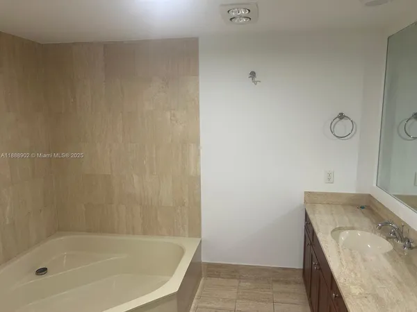 a bathroom with a granite countertop sink and a bathtub