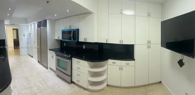 a kitchen with stainless steel appliances a microwave a stove and white cabinets