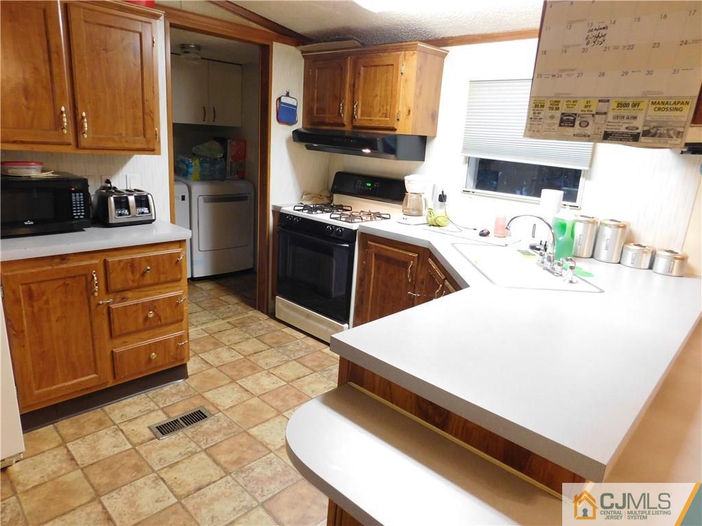 8 Ruffian Way, Unit 8 Howell, NJ 07731 - Photo 6 of 12 a kitchen with stainless steel appliances a sink a stove top oven a chimney and cabinets