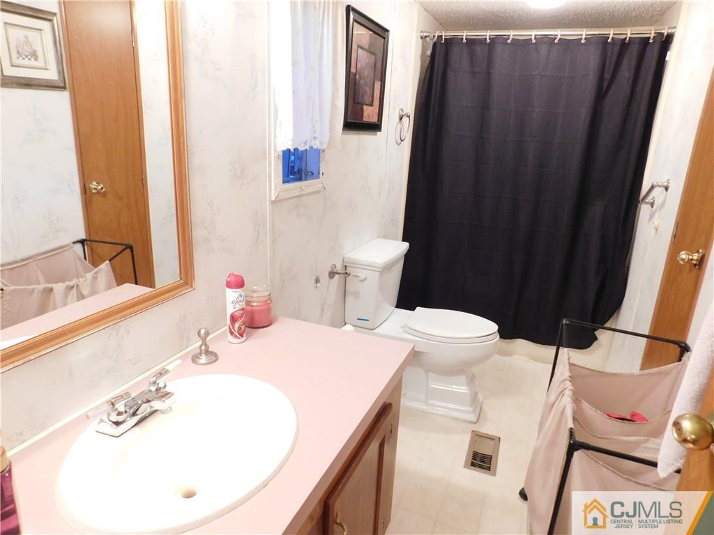 8 Ruffian Way, Unit 8 Howell, NJ 07731 - Photo 8 of 12 a bathroom with a sink a toilet and shower curtain