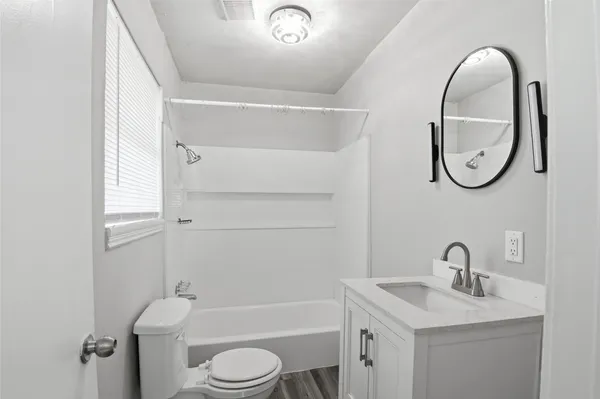 a bathroom with a toilet sink vanity tub and mirror