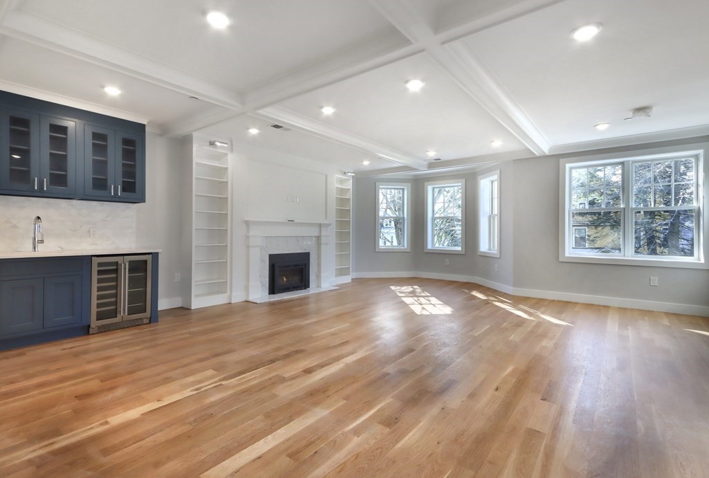 189 Babcock Street, Unit 2 Brookline, MA 02446 - Photo 18 of 39 an empty room with windows fireplace and wooden floor