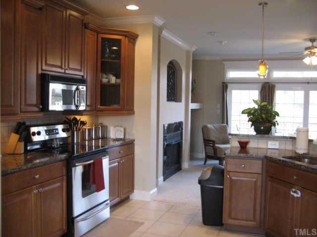 665 Cole Road Clayton, NC 27520 - Photo 5 of 12 Kitchen with light cherry cabinets, granite c-tops, tile backsplash, undercounter lighting and laminate tile flooring.