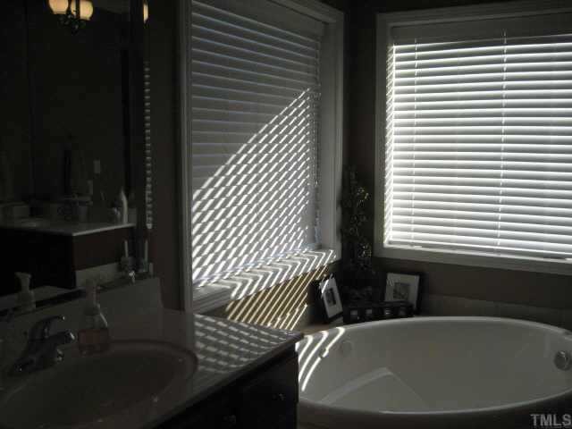 665 Cole Road Clayton, NC 27520 - Photo 9 of 12 Master bath with his and hers vanities, dressing table, corner jacuzzi tub / seperate tile shower and WIC.