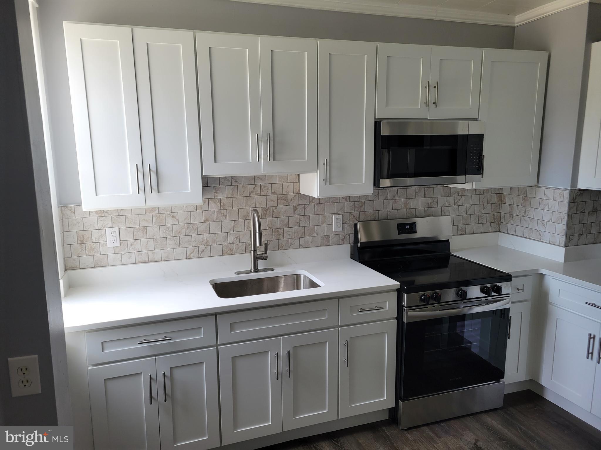 6757 Woodley Road Dundalk, MD 21222 - Photo 2 of 27 a kitchen with white cabinets and stainless steel appliances