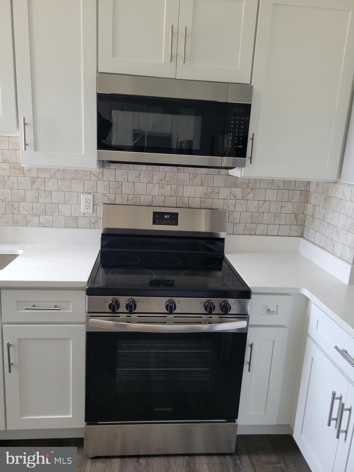 6757 Woodley Road Dundalk, MD 21222 - Photo 6 of 27 a kitchen with stainless steel appliances a stove a microwave and cabinets
