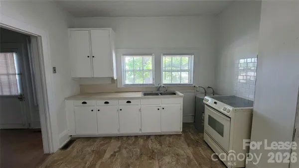 a kitchen with granite countertop a stove a sink and a refrigerator