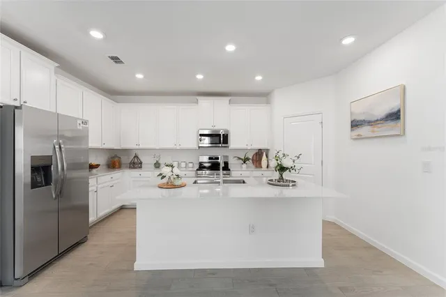 a kitchen with stainless steel appliances a sink a stove a refrigerator cabinets and a counter top space