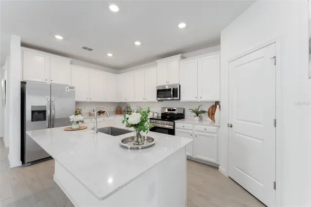 a kitchen with a sink stainless steel appliances and white cabinets