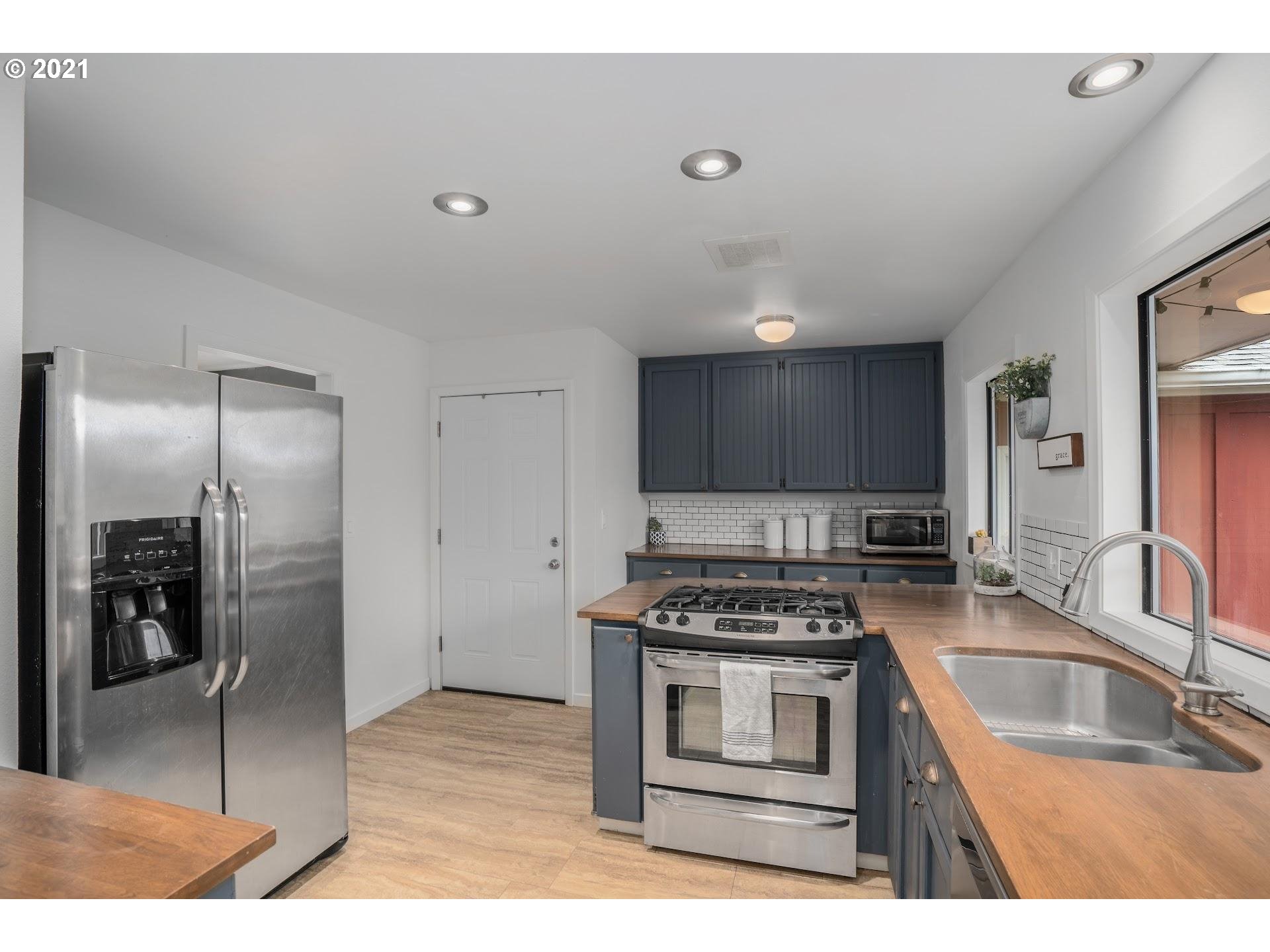 7408 Southwest Mapleleaf Street Portland, OR 97223 - Photo 11 of 32 a kitchen with stainless steel appliances granite countertop a sink stove and refrigerator
