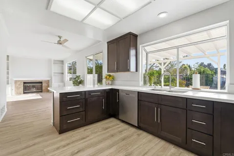 a kitchen with stainless steel appliances granite countertop a sink window and wooden cabinets