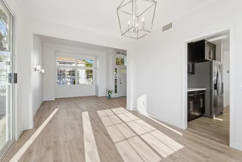 an empty room with wooden floor cabinet and windows