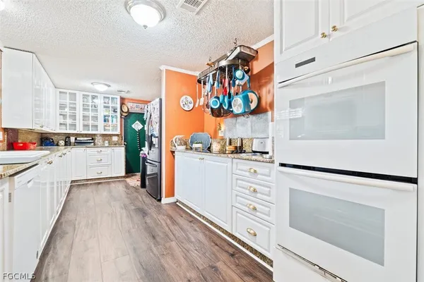 a kitchen with stainless steel appliances white cabinets and wooden floor