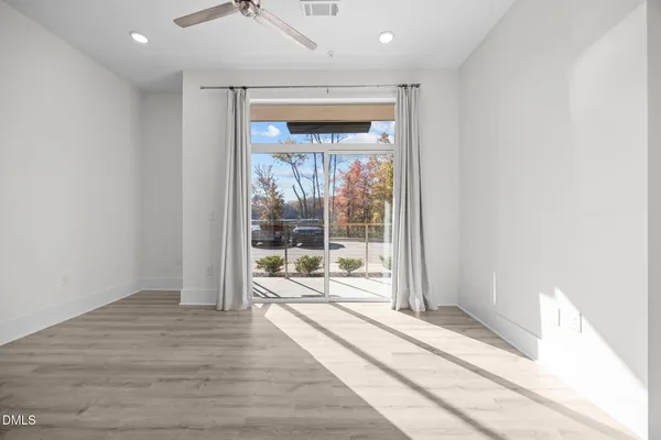 a view of a hallway with wooden floor and a room
