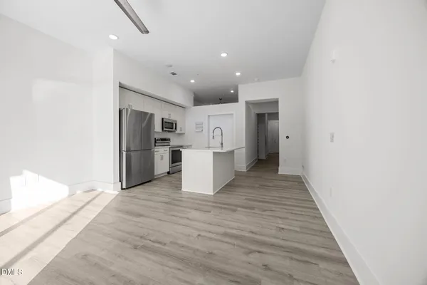 a view of kitchen with refrigerator microwave and white cabinets