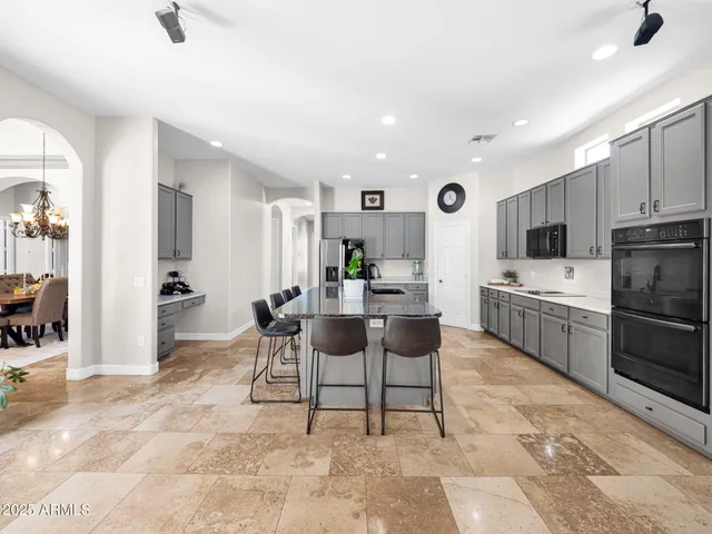 a kitchen with stainless steel appliances granite countertop a table chairs sink and cabinets