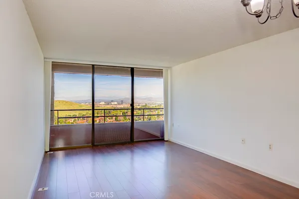an empty room with wooden floor and windows with curtains
