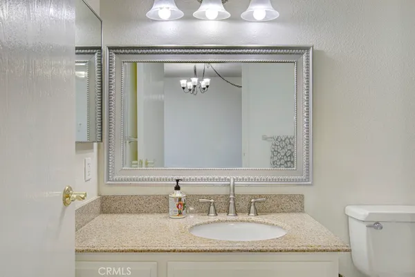 a bathroom with a granite countertop sink and a mirror