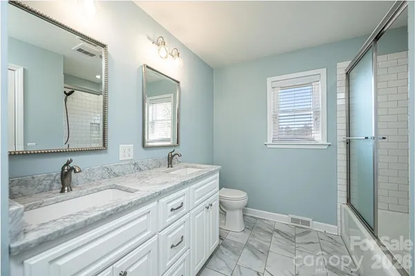 a bathroom with a granite countertop sink mirror vanity and toilet