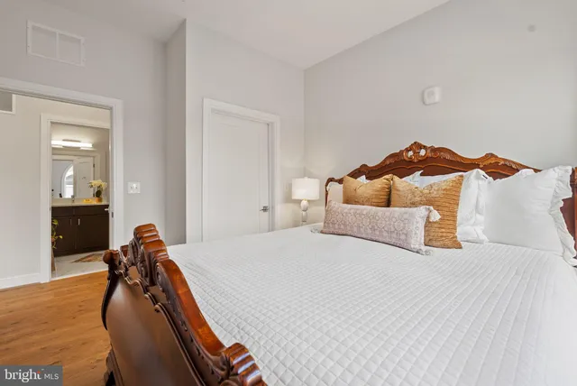 a bedroom with a bed and a large mirror next to a window