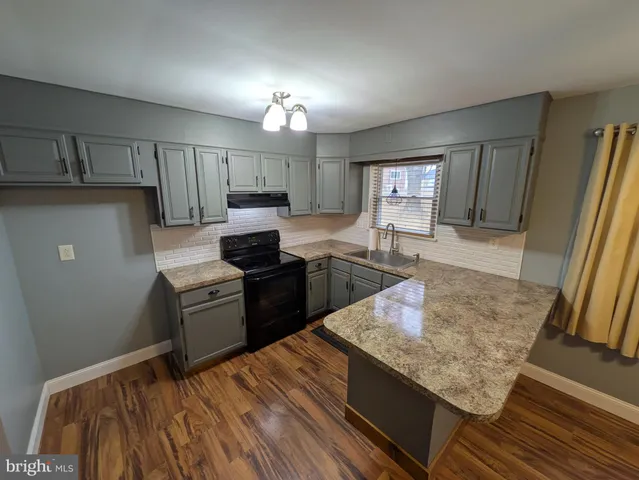 a kitchen with granite countertop a sink dishwasher stove and cabinets