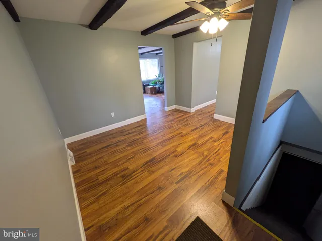 a view of an empty room with wooden floor and a ceiling fan