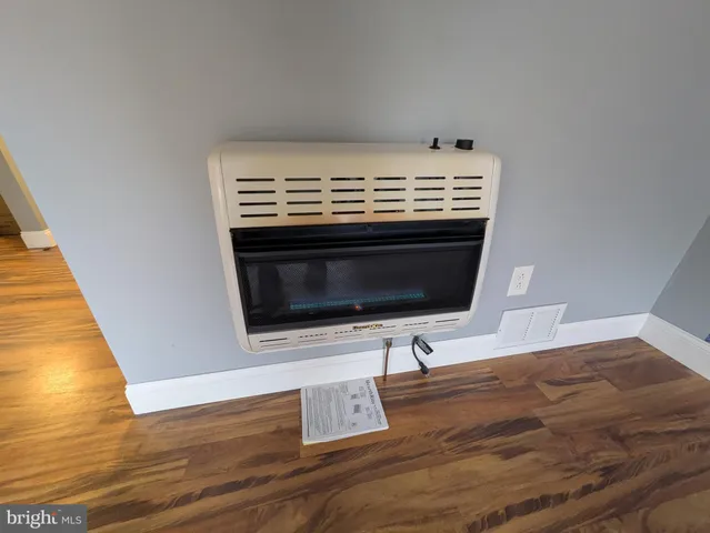 a view of an empty room with wooden floor and fireplace
