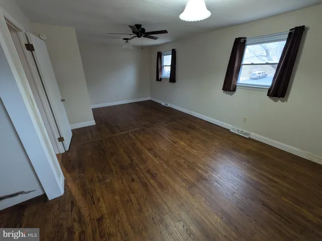 a view of empty room with wooden floor and fan