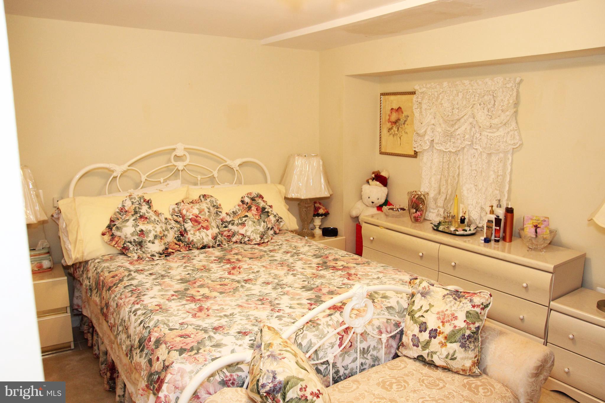 3413 Dunnington Road Beltsville, MD 20705 - Photo 15 of 16 a large bed sitting in a bedroom next to a window with potted plants