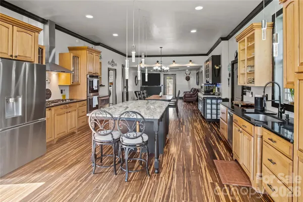 a living room with stainless steel appliances furniture a rug and a kitchen view