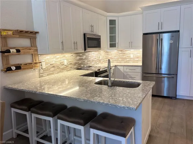 a kitchen with granite countertop a sink stove and refrigerator