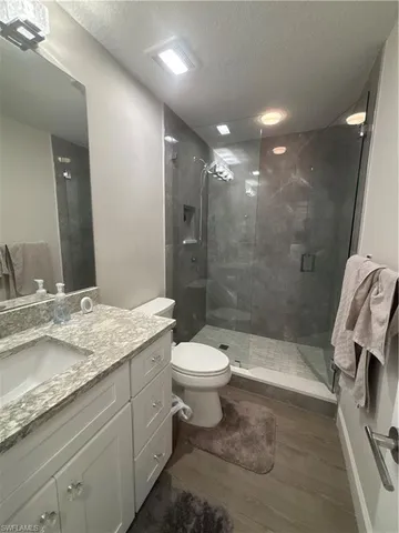 a bathroom with a granite countertop toilet sink and mirror