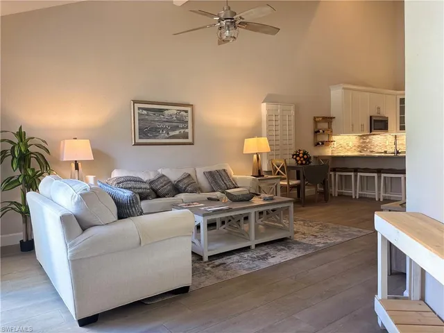 a living room with furniture kitchen view and a window