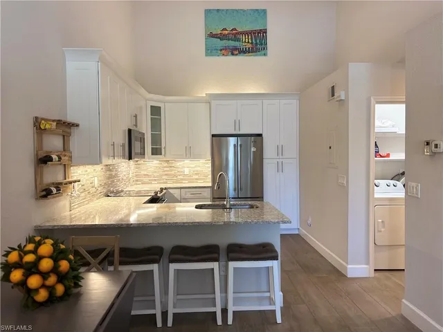 a kitchen with stainless steel appliances kitchen island granite countertop a table chairs in it and wooden floors