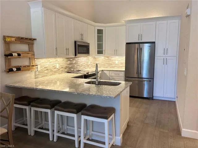 a kitchen with granite countertop a stove refrigerator and microwave