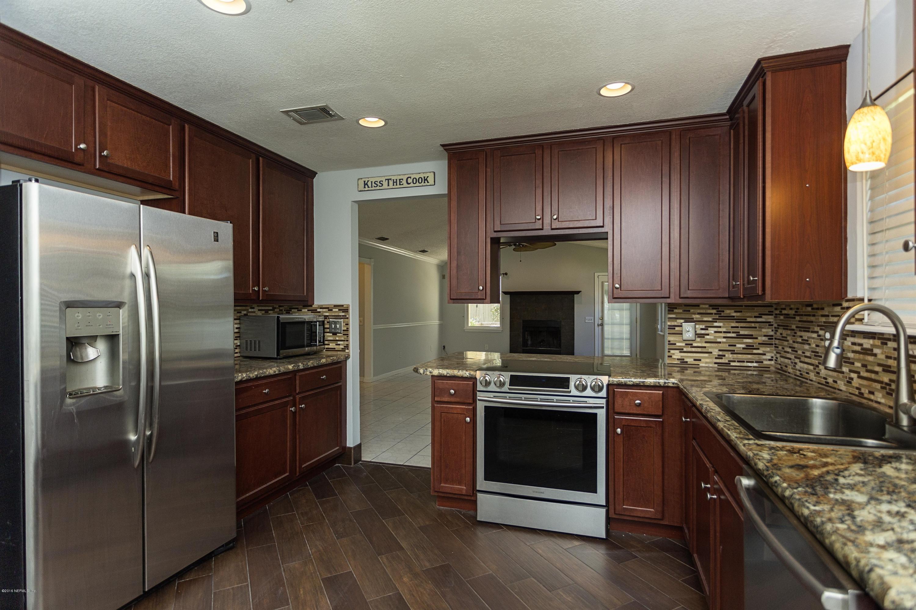 12782 Attrill Road Jacksonville, FL 32258 - Photo 9 of 25 a kitchen with a refrigerator sink and wooden cabinets