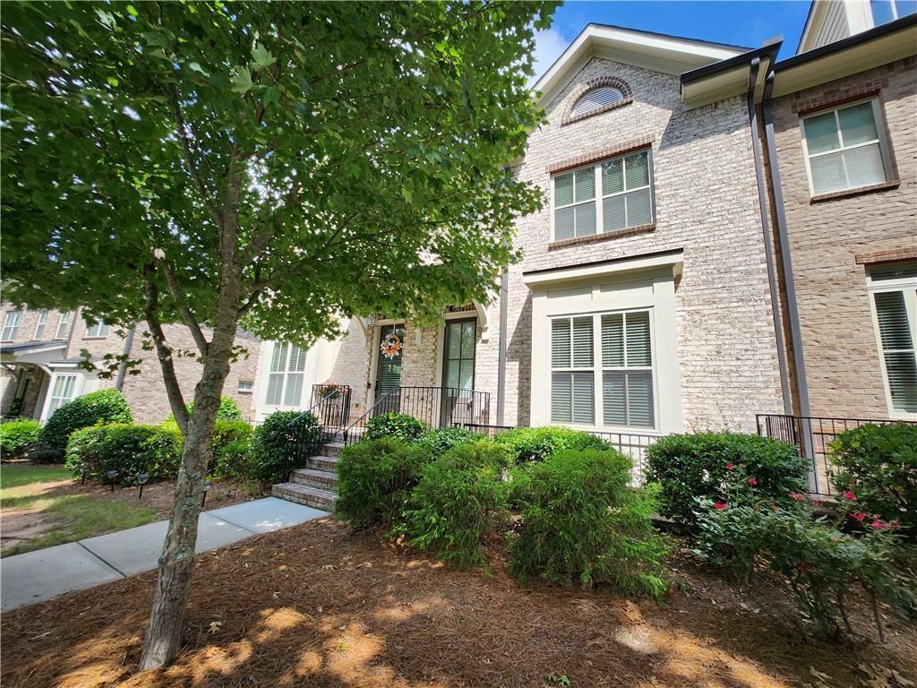 1323 Faircrest Way Suwanee, GA 30024 - Photo 2 of 16 a view of a white house next to a yard with potted plants and large trees